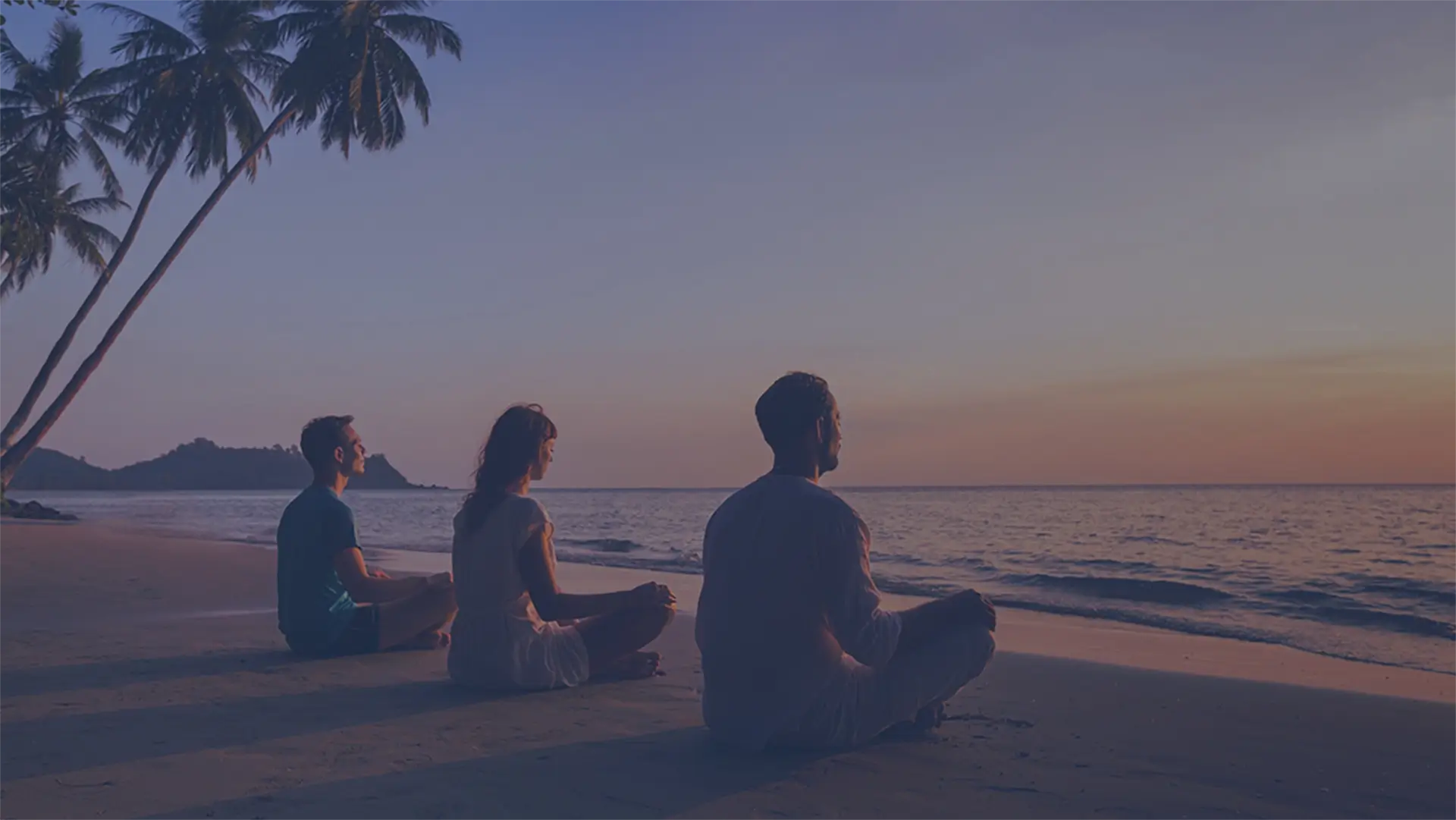 tre personer som mediterer på en strand